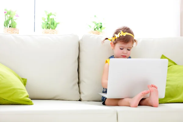 Kind meisje met een laptop thuis — Stockfoto