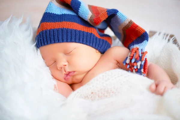 Симпатичный новорожденный ребенок в синей вязаной кепке спит в корзине — стоковое фото