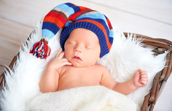 Mignon nouveau-né en bonnet en tricot bleu dormant dans le panier — Photo