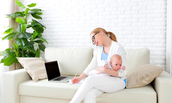 Business  mother works at home via Internet with newborn baby — Stock Photo, Image