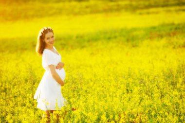 Yaz doğa çayır sarı flo ile güzel hamile kadın