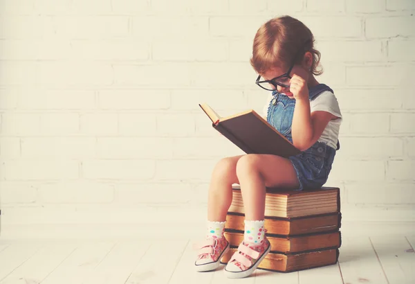Дитяча маленька дівчинка в окулярах читає книжки — стокове фото
