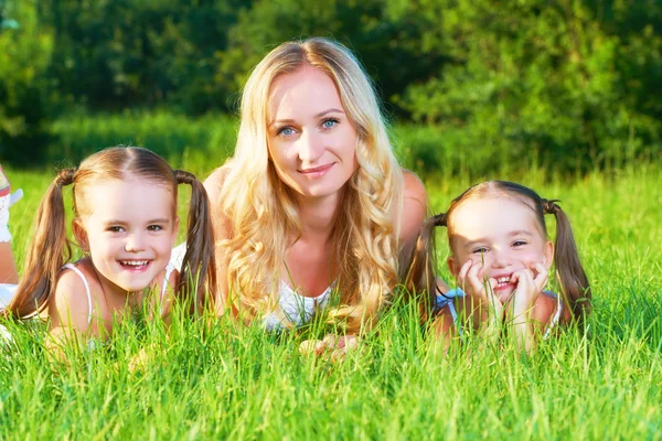Família feliz mãe e filhos irmãs gêmeas no prado no summe — Fotografia de Stock