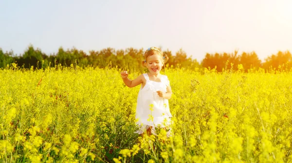 Gelukkig kind meisje uitgevoerd op veld met gele bloemen — Stockfoto