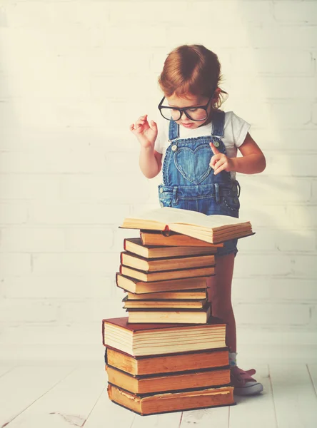 Kind meisje met glazen een lezing — Stockfoto