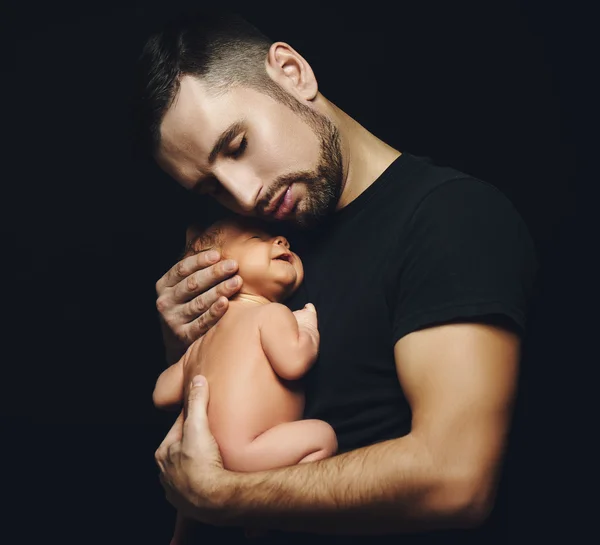 Newborn baby sleeping in his arms of father on dark — Stock Photo, Image