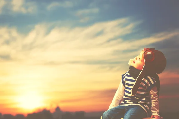 Happy child dreams of becoming pilot aviator on sky sunset backg — Stock Photo, Image