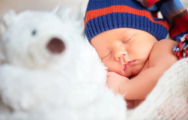 Newborn baby in knit cap and teddy toy bear sleeping — Stock Photo, Image