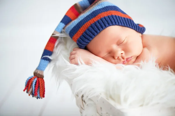 Bebê recém-nascido bonito em azul tricô cap dormindo em cesta — Fotografia de Stock