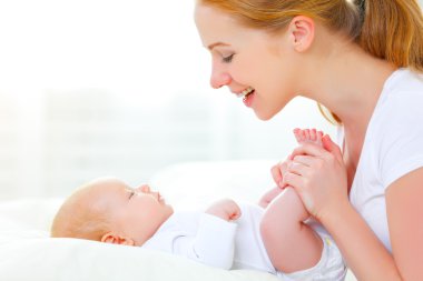Mutlu aile annesi yeni doğmuş bebekle oynuyor.
