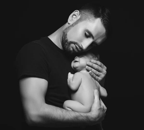 Newborn baby sleeping in his arms of father on dark — Stock Photo, Image