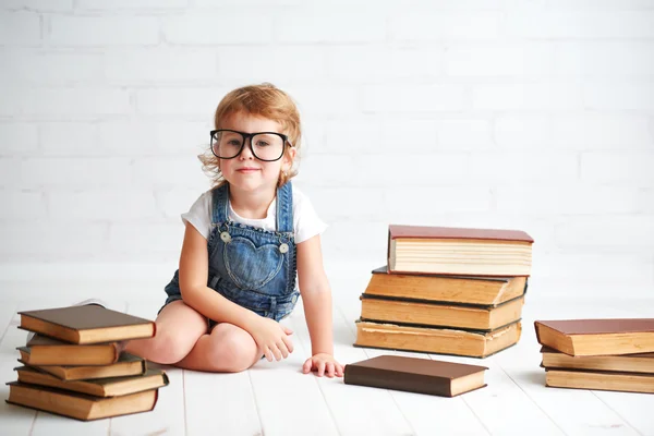 Criança menina com óculos lendo um livros — Fotografia de Stock
