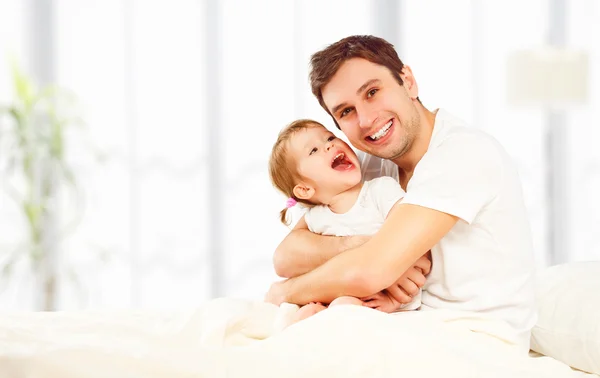 Счастливый отец семьи и дочь, играющие в постели — стоковое фото