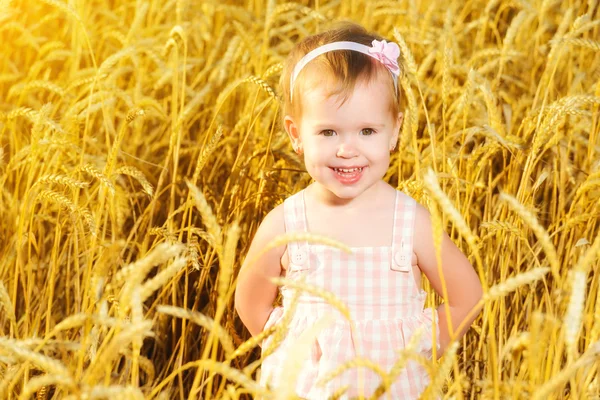 Glückliches kleines Mädchen in einem Feld aus goldenem Weizen im Sommer — Stockfoto