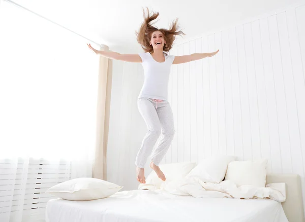 Happy girl jumping and having fun in bed — Stock Photo, Image