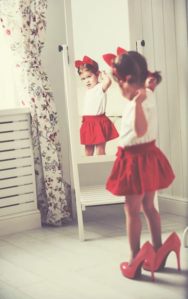 Little girl child fashionista looking in the mirror at home — Stock Photo, Image