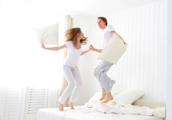 Pasangan bahagia melompat dan bersenang-senang di tempat tidur — Stok Foto