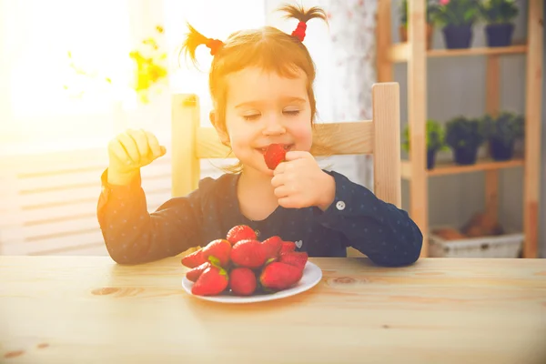 Glückliches Kindermädchen isst Erdbeeren in Sommerhausküche — Stockfoto