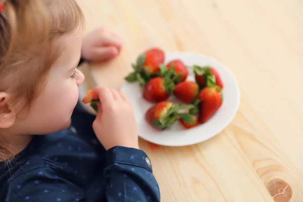 Felice bambina ragazza mangia fragole in cucina casa estate — Foto Stock