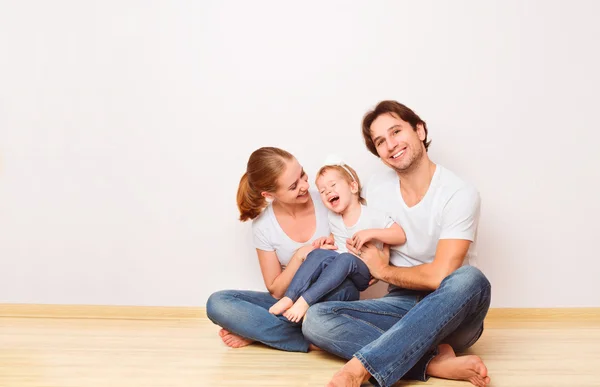 Lycklig familj på golvet nära tom vägg i lägenheten köpte — Stockfoto