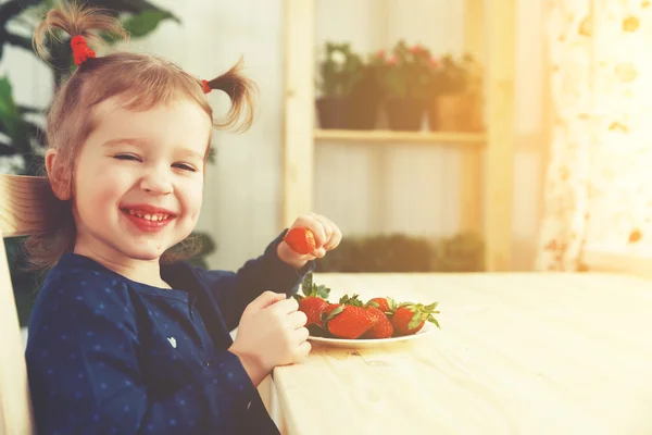 Felice bambina ragazza mangia fragole in cucina casa estate — Foto Stock