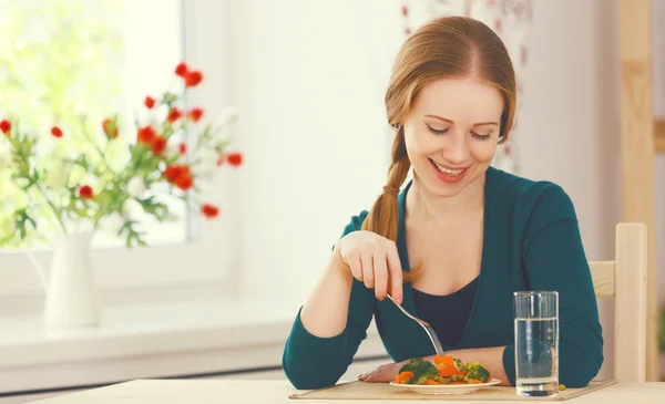 Joven mujer sana come verduras en casa en la cocina — Foto de Stock