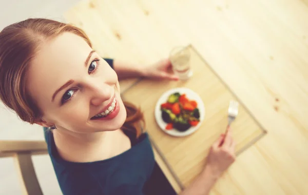 Joven mujer sana come verduras en casa en la cocina Imágenes De Stock Sin Royalties Gratis