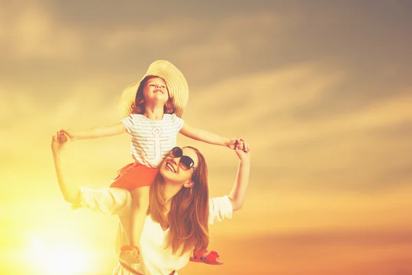 Família feliz mãe e filha na praia ao pôr do sol — Fotografia de Stock