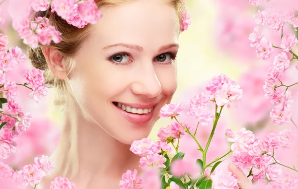 Schoonheid gezicht van jonge mooie vrouw met roze bloemen — Stockfoto