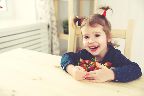 Glückliches Kindermädchen isst Erdbeeren in Sommerhausküche — Stockfoto