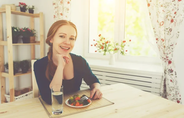 Молодая здоровая женщина ест овощи дома на кухне — стоковое фото