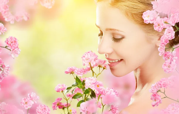 Piękna twarz młodej kobiety piękne z różowe kwiaty w jej ha — Zdjęcie stockowe