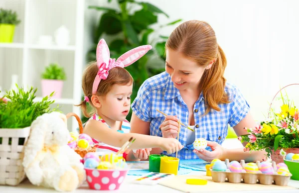 Feliz familia madre e hijo niña pinta huevos para Pascua — Foto de Stock