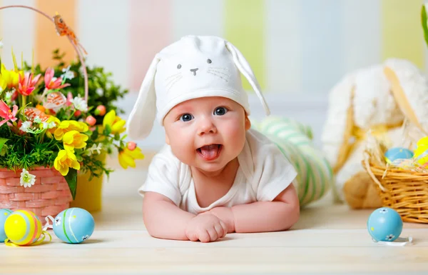 Niño feliz bebé con orejas de conejo de Pascua y huevos y flores — Foto de Stock