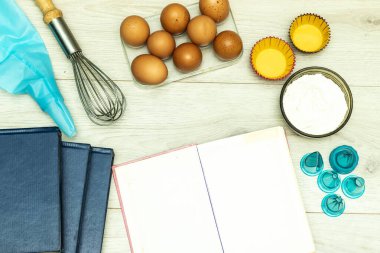 Ahşap masada boş yemek tarifi kitabı, yumurta ve un.