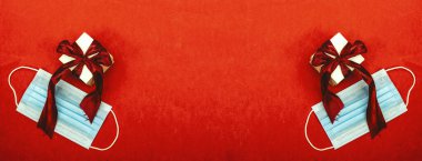 Kırmızı arka planda yüz maskesi olan küçük hediye kutusu, sağlıklı tatil konsepti.