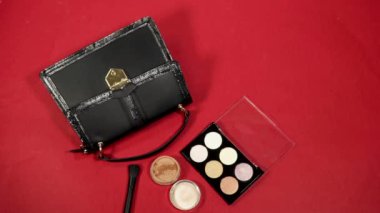 Kırmızı arka planda siyah deri çantalı.