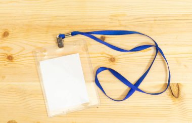 Boş rozet maketi ahşap masada izole edilmiş. Boş isim etiketi, boynuna ip geçirilmiş gibi yap. İsim Etiketi, Şirket Tasarımı.