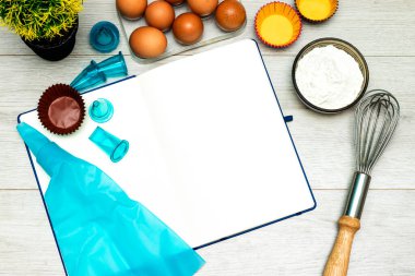 Ahşap masada boş yemek tarifi kitabı, yumurta ve un.