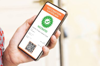 Coronavirus covid-19 aşısı olduğunu onaylamak için elinde dijital aşı sertifikası olan cep telefonu tutan bir kadın.