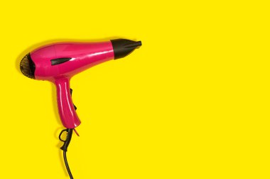 Sarı arka planda siyah ve pembe saç kurutma makinesi var. Küçük Ev Aletleri. Ev aletleri mi? Elektrikli Ev Aletleri. Profesyonel Saç Biçimi Aracı