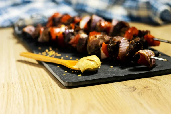 羊マスタードソースと黒ボード上の赤唐辛子と玉ねぎの野菜と肉串 — ストック写真