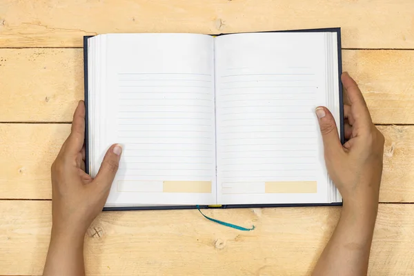 Ruce Držící Knihu Agendy Nebo Notebook Izolované Dřevěném Stole — Stock fotografie