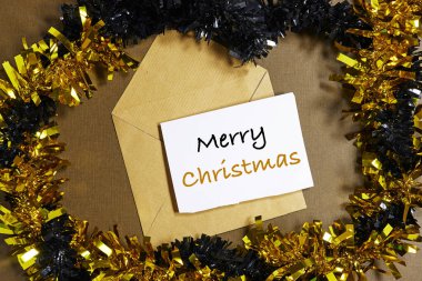 Kraft Zarfındaki Mutlu Noeller Kartı Altınla ve Siyah Tinsel Çelenklerle çevrili