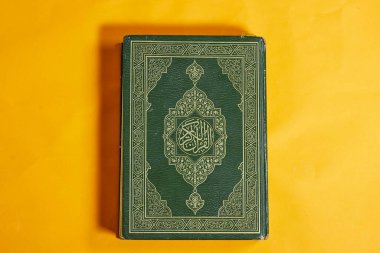 Yeşil kapaklı Arapça kaligrafisi olan Kur 'an' ın kapalı bir kopyası. Arapça 'da, Kuran-ı Kerim, yani Kuran-ı Kerim okunur. Eğitimsel ve kültürel amaçlar için görüntü