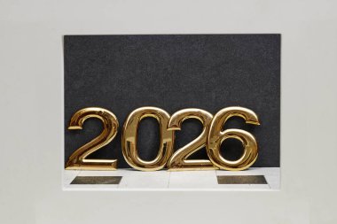 Koyu bir zemin üzerine kurulmuş parlak altın 2026 haneli bir sergi, kutlama, ilerleme ve yeni yıl için ileriye dönük planlar sunuyor.