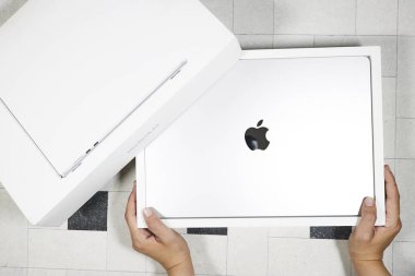 Mascara, Cezayir - 5 Kasım 2025: Bir çift el, Apple logosu ile gümüş renkli bir MacBook Air M4 2025 'i gözler önüne sermek için minimalist beyaz bir kutu açıyor.