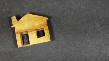 Beyaz dantele sarılı kırmızı bir kalp dekoru eşliğinde ahşap minyatür bir ev. Evi ve sevgiyi sembolize ediyor. Sıcak ve duygusal bir ruh hali yaratıyor.