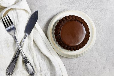 Tabakta keten kumaş ve gümüş çatal bıçak seti olan çikolatalı tart.