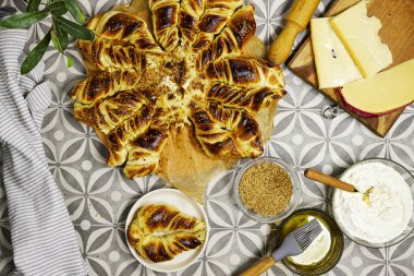 Lezzetli Türk Ramazan Altın Örülmüş Yıldız Ekmeği Peynirli, Tereyağlı, peynirli, unlu, susamlı tohumlarla çevrili bir masada oturuyor.